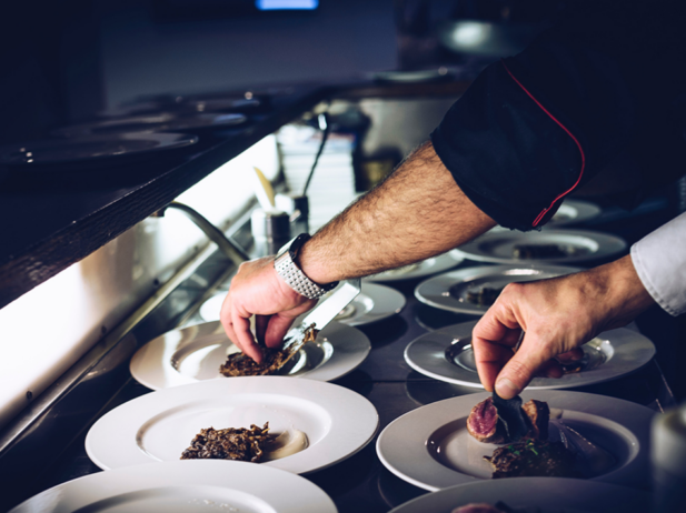 picture of hands plating gourmet dishes of food at a restaurant