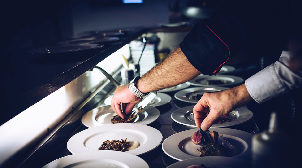 picture of hands plating gourmet dishes of food at a restaurant