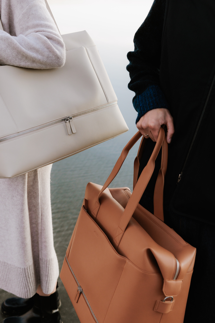 Two people carrying beige and tan monos weekender bags.