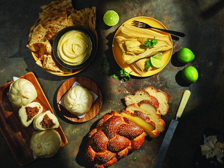 Clockwise, from top left: hummus from the European Deli, jalapeno and cheese tamales from Antojos y Sabores, challah from Livia, steamed pork buns from New Town Bakery. Photo: Clinton Hussey. Styling: Lawren Moneta.
