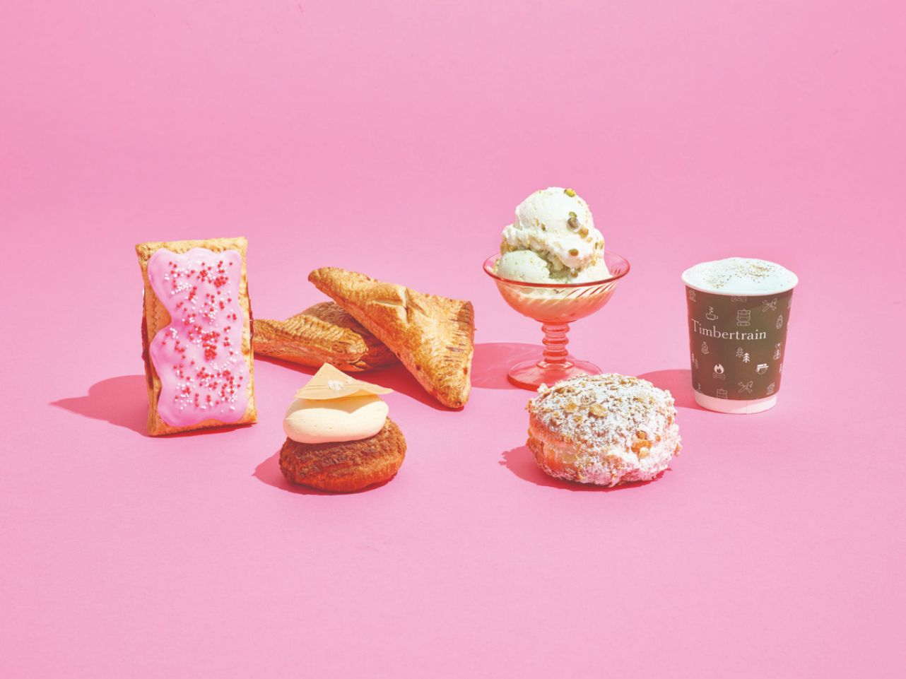 a pop tart, dish of ice cream, donut, coffee and pastry all sit on a pink background