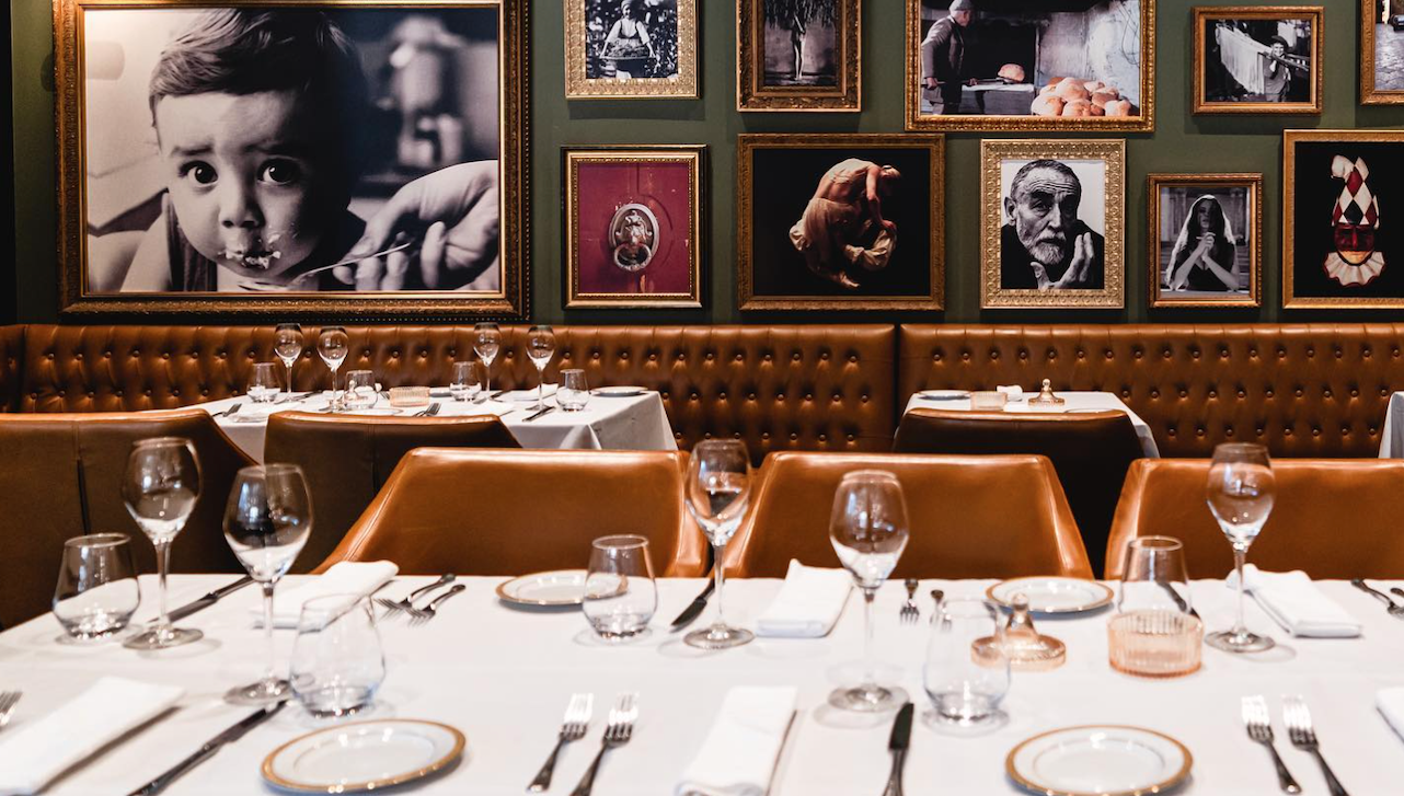 Table set up in the foreground with picture frames hanging on a green wall in the background.