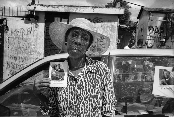Black and White image from film of Black Woman holding a photograph on the street.