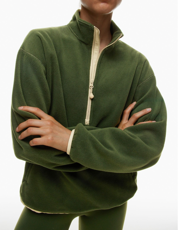 someone is wearing a green sweater and crossing their arms in front of their chest; their face is cropped out of the photo