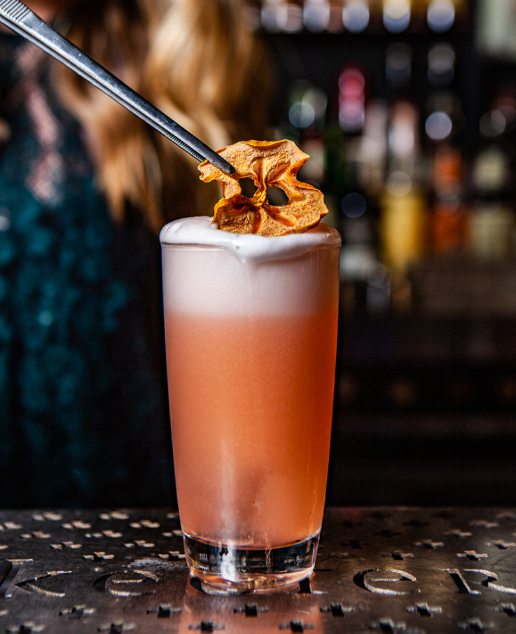 orange-coloured cocktail on a dark bar