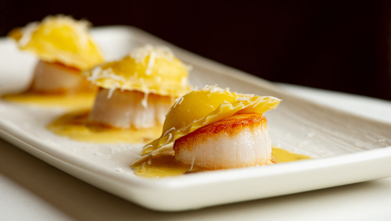 Three pieces of scallop with ravioli on top.