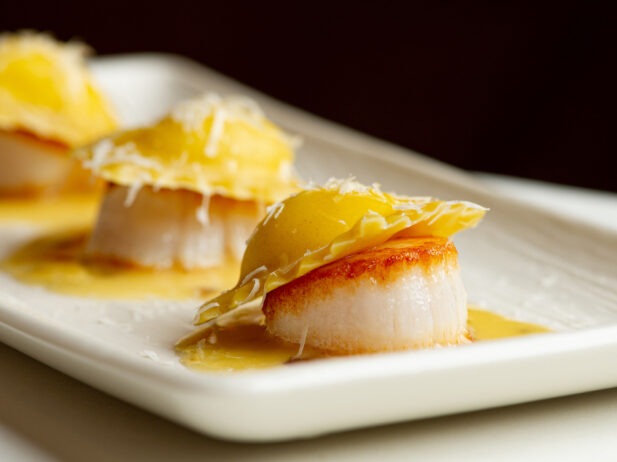 Three pieces of scallop with ravioli on top.