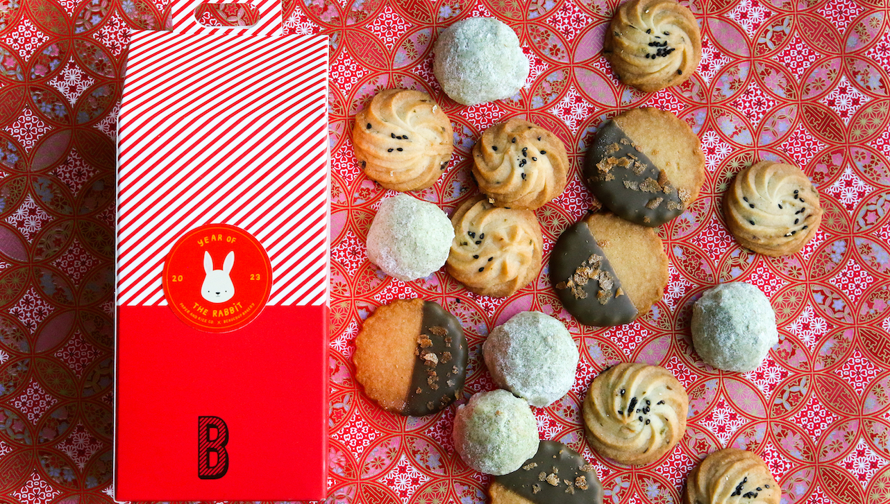 Cookie box and cookies scattered on red decorative paper.