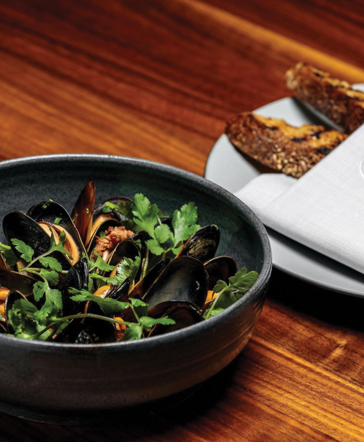 a dish of mussels on a dark wood table