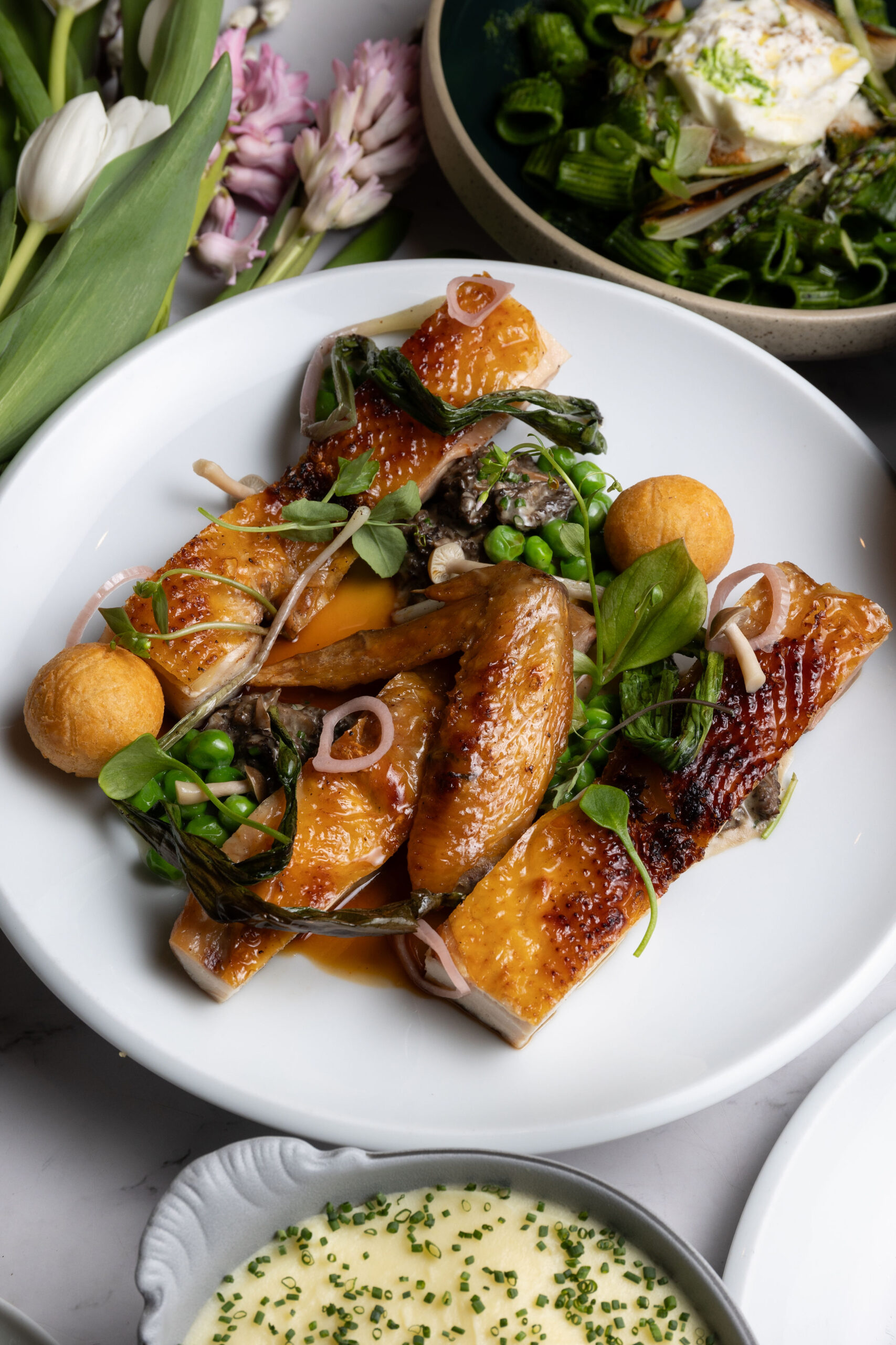 An artfully plated Chinese food dish surrounded by greenery.