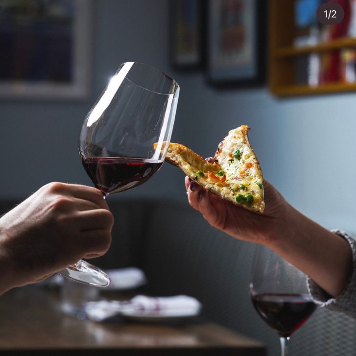 A slice of pizza and glass of wine cheers