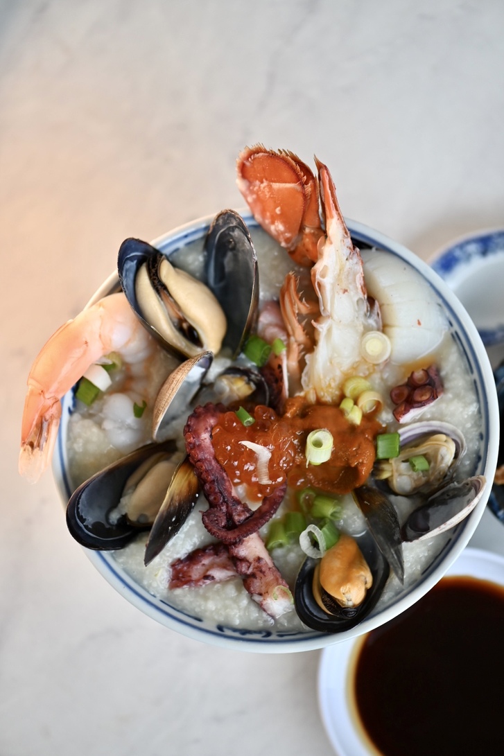 Above shot of congee bowl with seafood and sauce on side