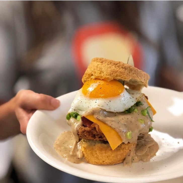 Biscuit topped with fried chicken, cheese, gravy, and an egg. 