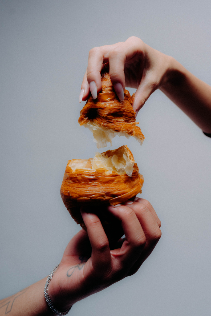 A butter croissant being pulled in two. 