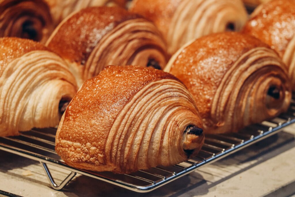 Fresh-baked chocolate croissants on a cooling rack.