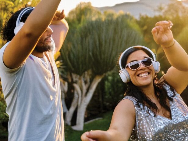 Two people wearing headphones dancing outside.