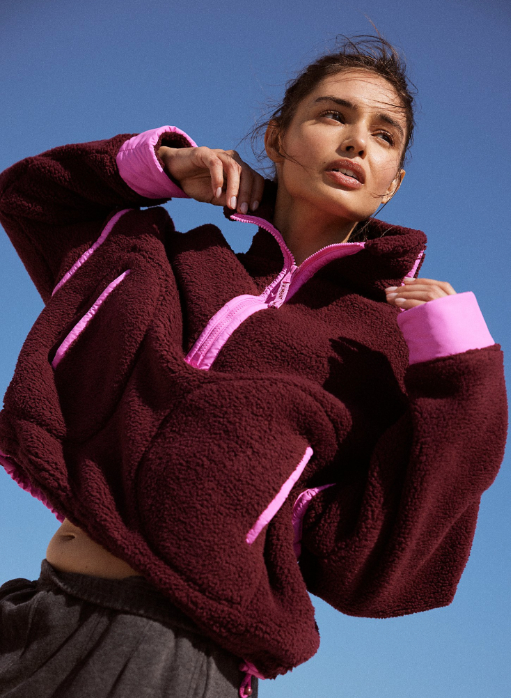 woman wearing purple half-zip sweatshirt on a blue background