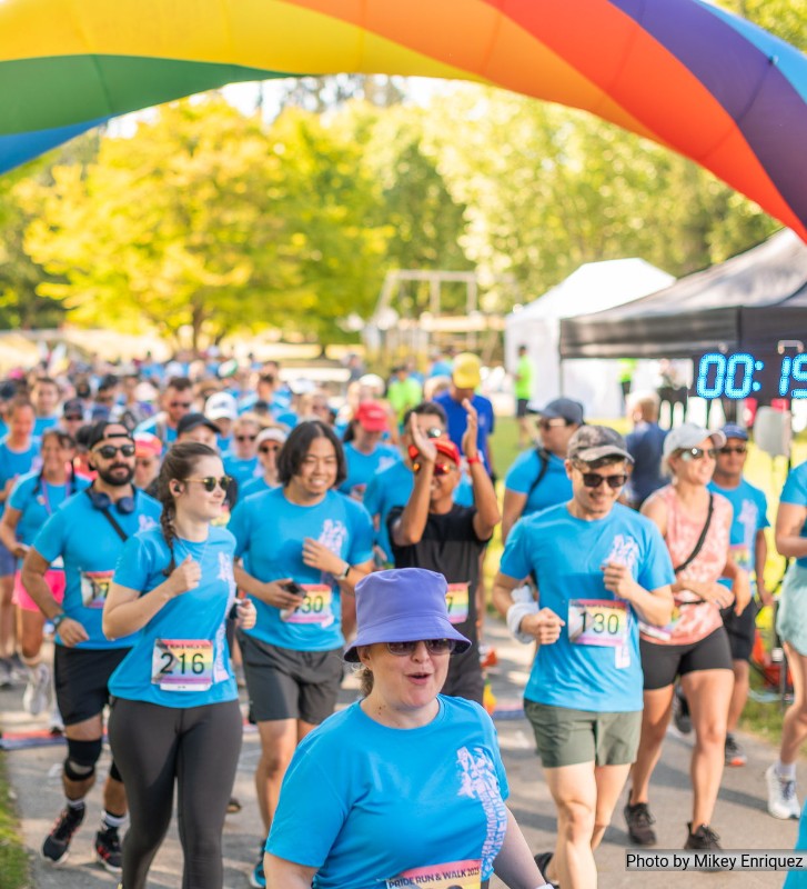 People running in a marathon during a pride parade. dressed in blue shirts 