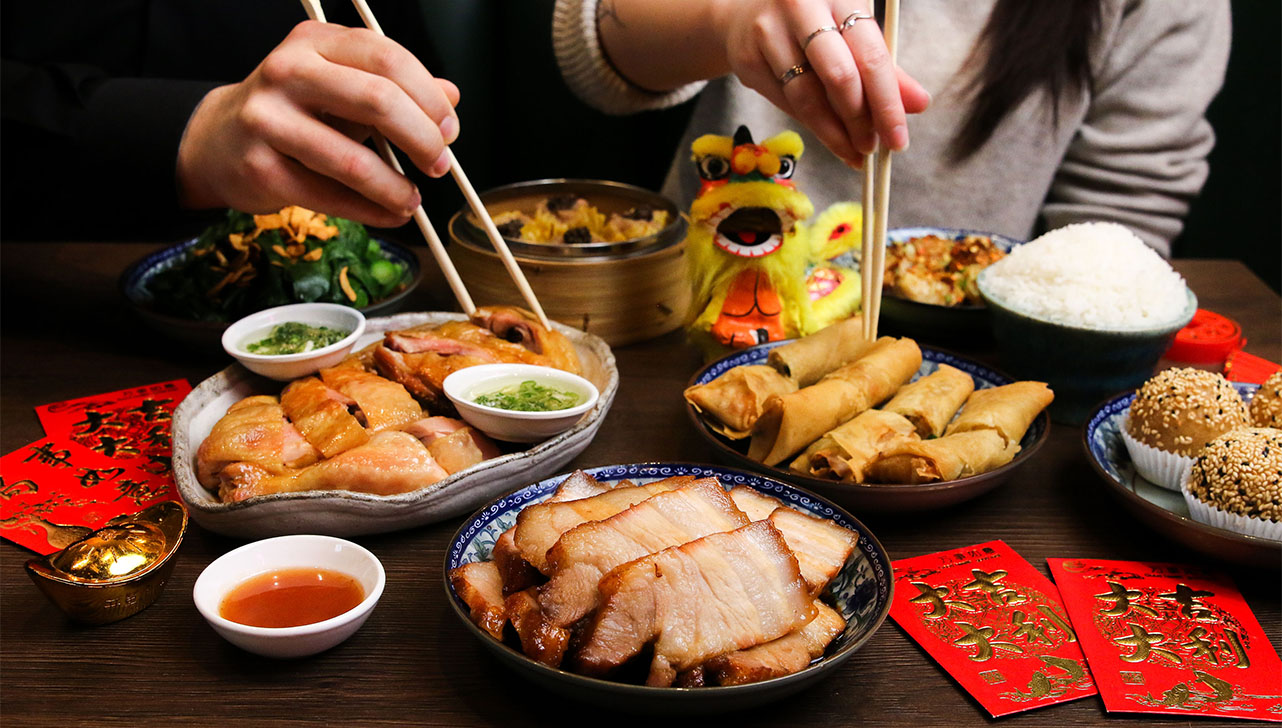 Two hands picking up Chinese food with chopsticks.