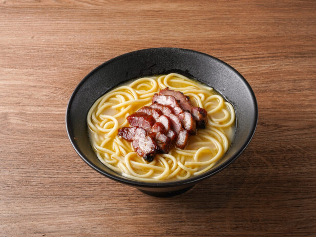 A bowl of thick noodles and BBQ pork