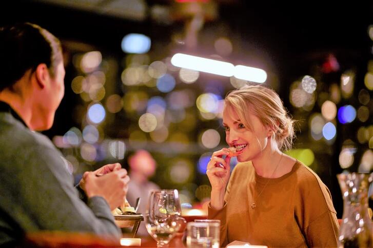 A woman eating at a restaurant across from a man. 