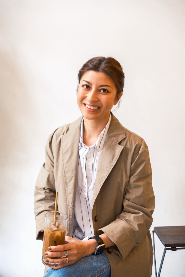 A smiling woman in a beige blazer. 
