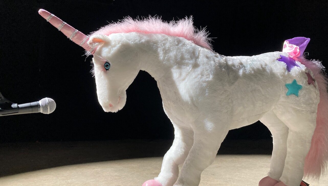 Unicorn stuffed toy in front of microphone.
