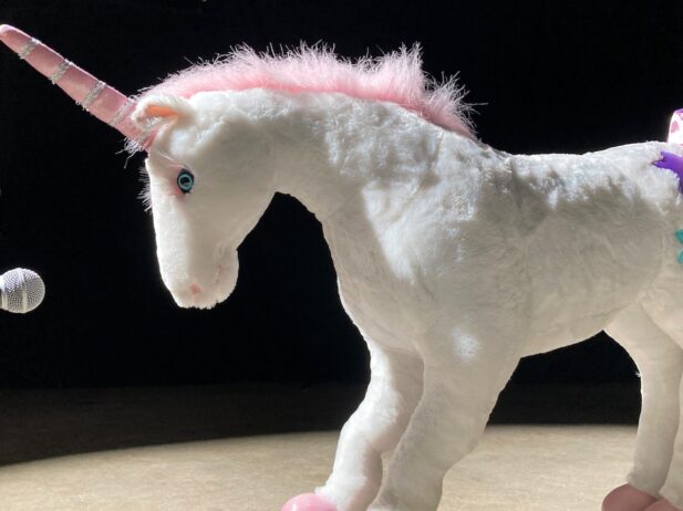 Unicorn stuffed toy in front of microphone.