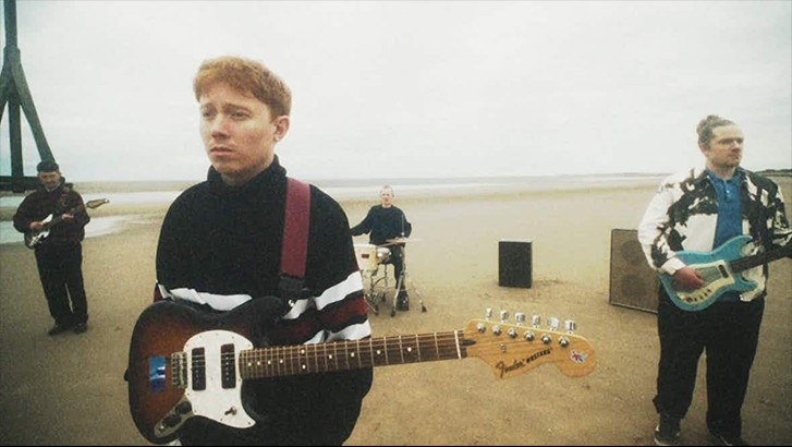 Band with lead singer holding instruments on a foggy beach