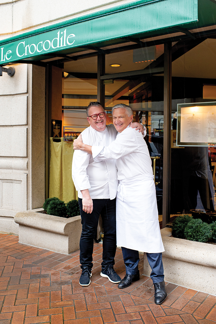 rob and michel in chef coats hugging and smiling outside of le crocodile