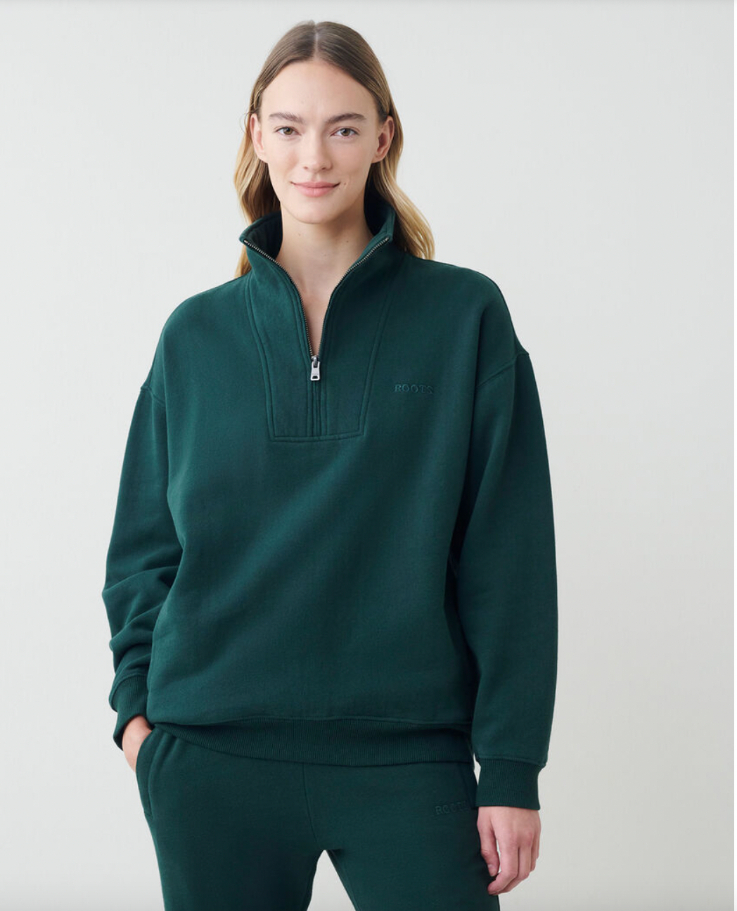 a woman with long hair wearing a dark-green, over-sized half-zip sweatershirt