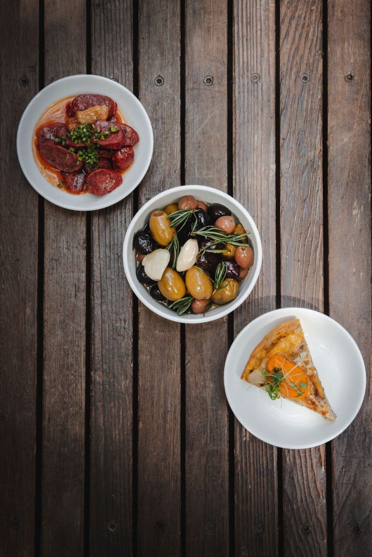 3 small plates with dishes. Olives, a savory pie and a meat dish