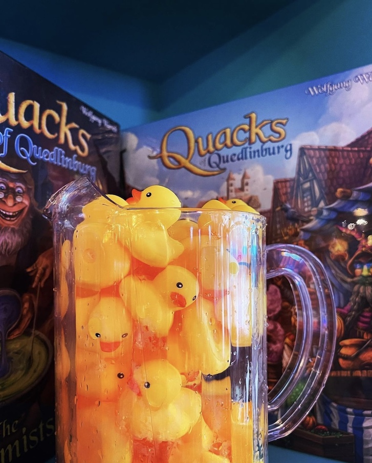 A jar of rubber ducks in front of two board games. 