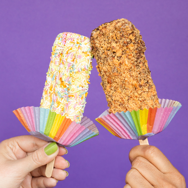 two hands holding sprinkle-coated ice cream bars that are touching