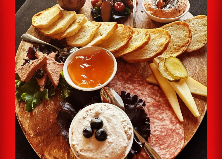 Charcuterie board with crackers, dip, meat, cheeses. 