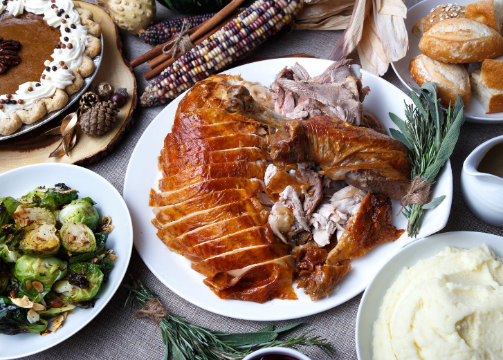 Thanksgiving spread with turkey, brussel sprouts, mashed potatoes, and pie. 