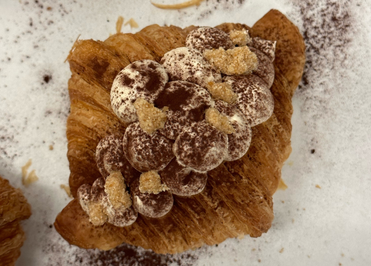 Croissant with crumble on top on a white counter. 
