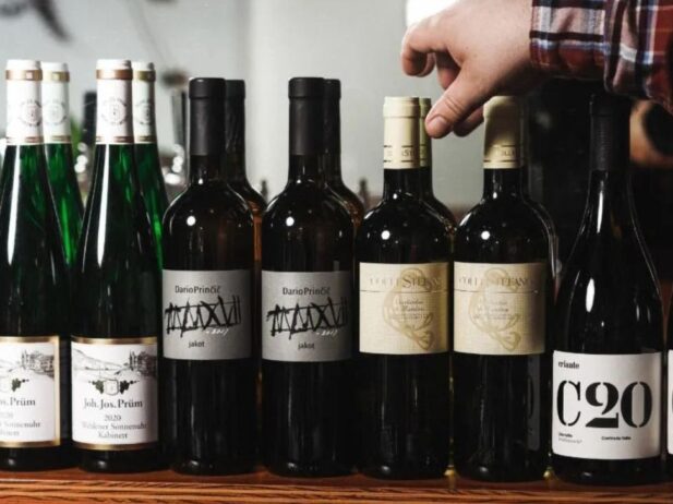 Wine bottles in a row with a hand reaching for one