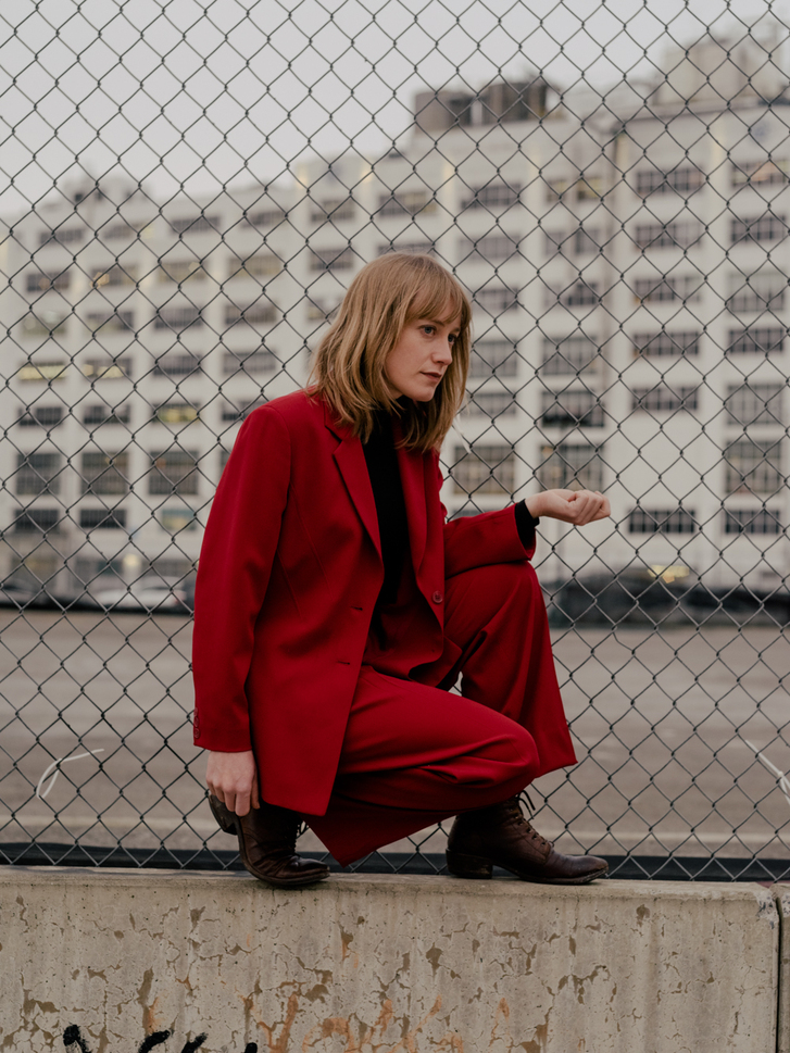 Tamara Lindeman in a red suit crouched near a chain link fence