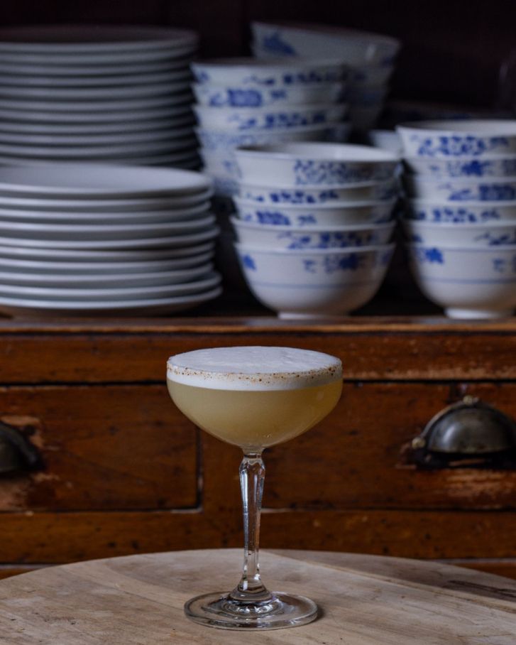 egg-white-topped cocktail on a wooden table