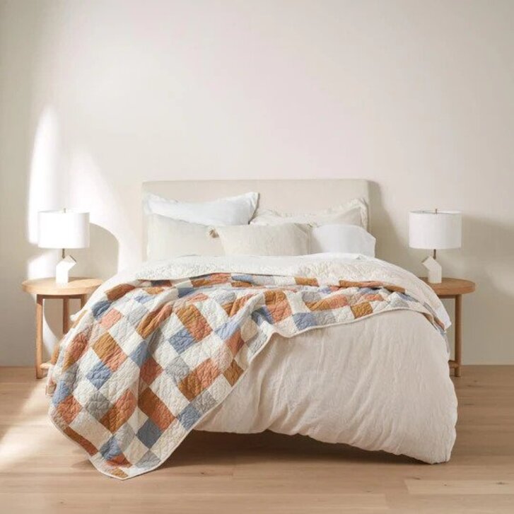 A bed with a checkered quilt draped on it