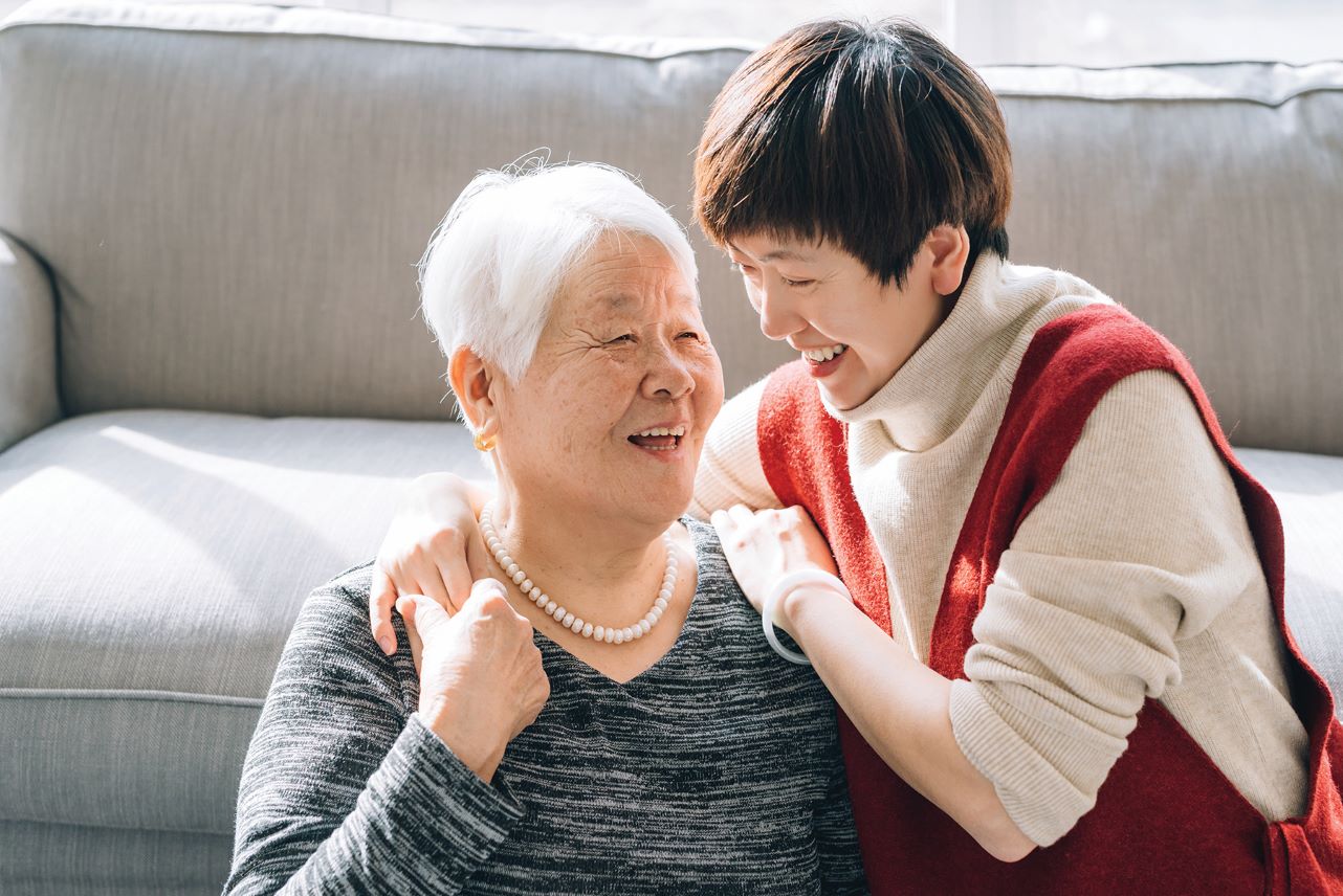 Middle aged woman embracing elderly woman.
