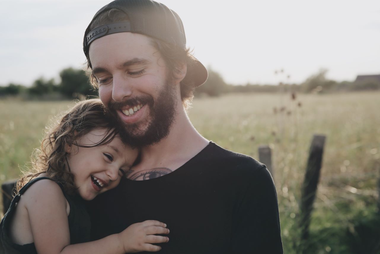 Father holding daughter in a field.