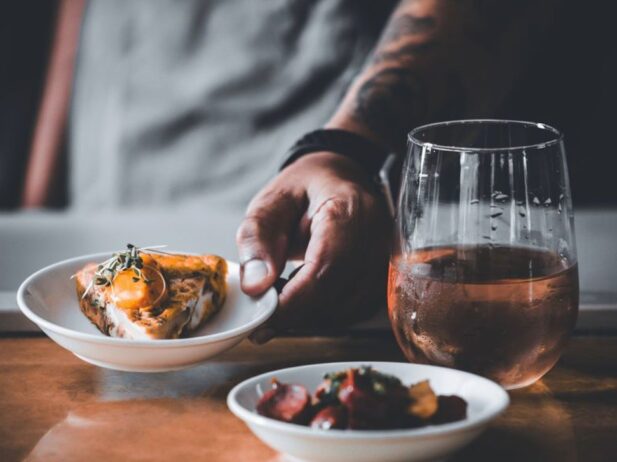A glass of rose, as well as two small plates with dishes.
