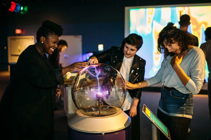 a group of 20 somethings interacting with an electric ball exhibit